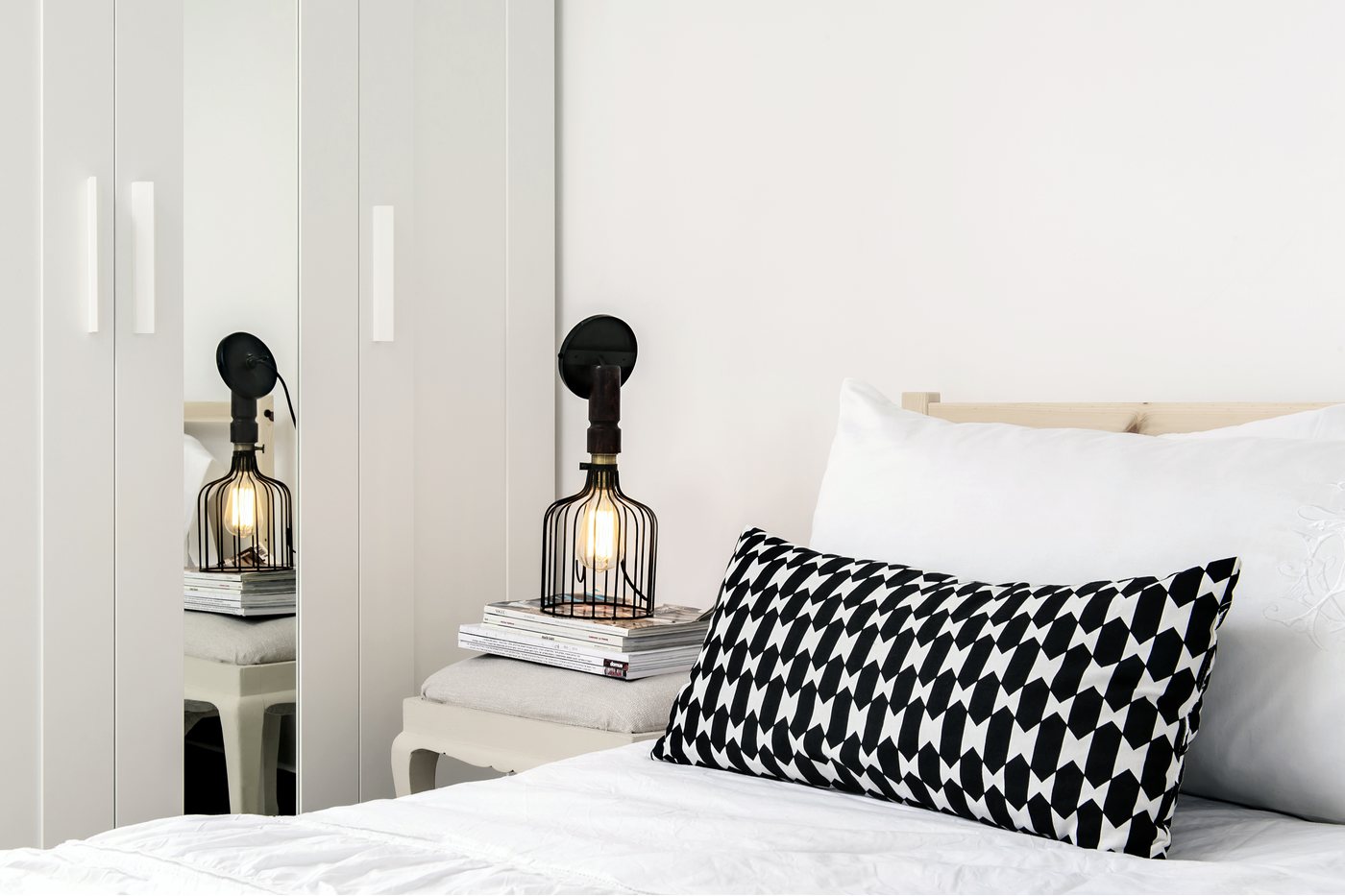 A serene modern bedroom with sculptural sconces and a quiet black and white palette.