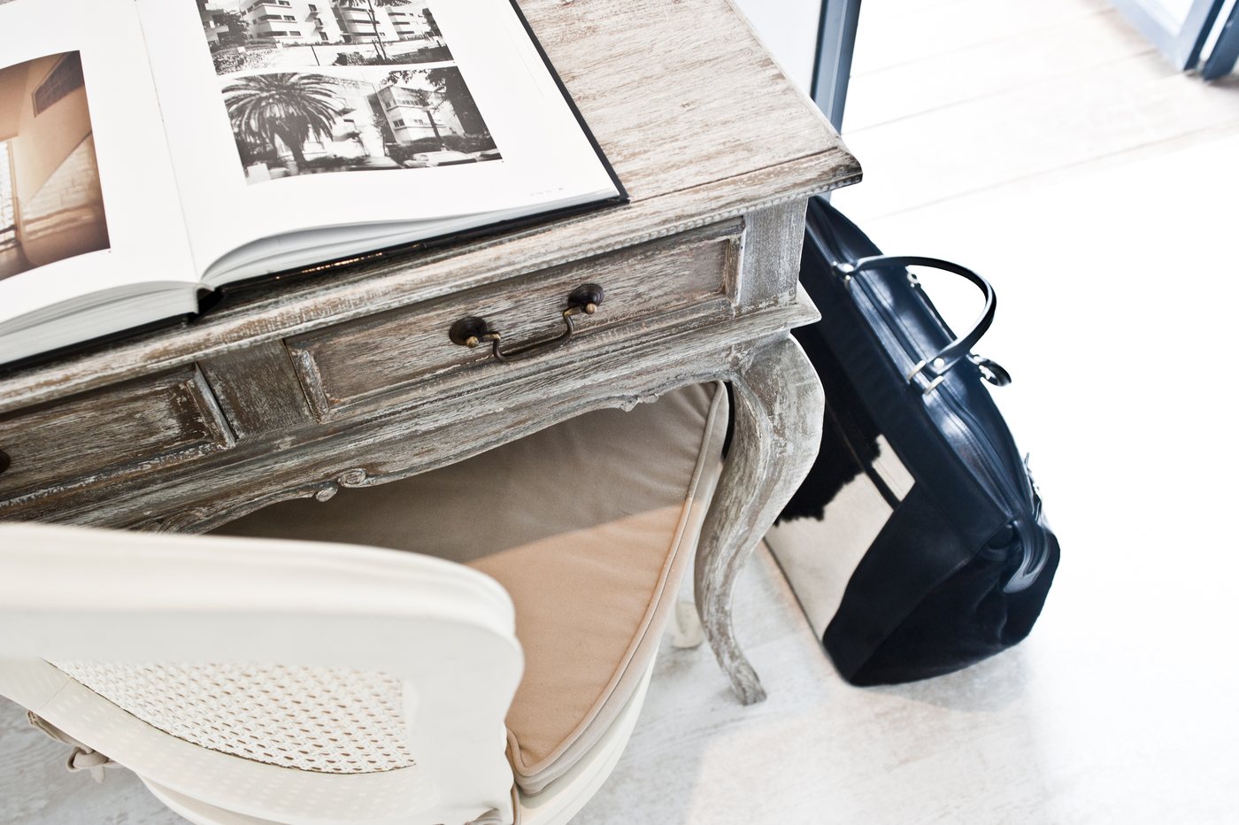 A Professional Shopping Day vignette with a French country desk, design book and curated finds