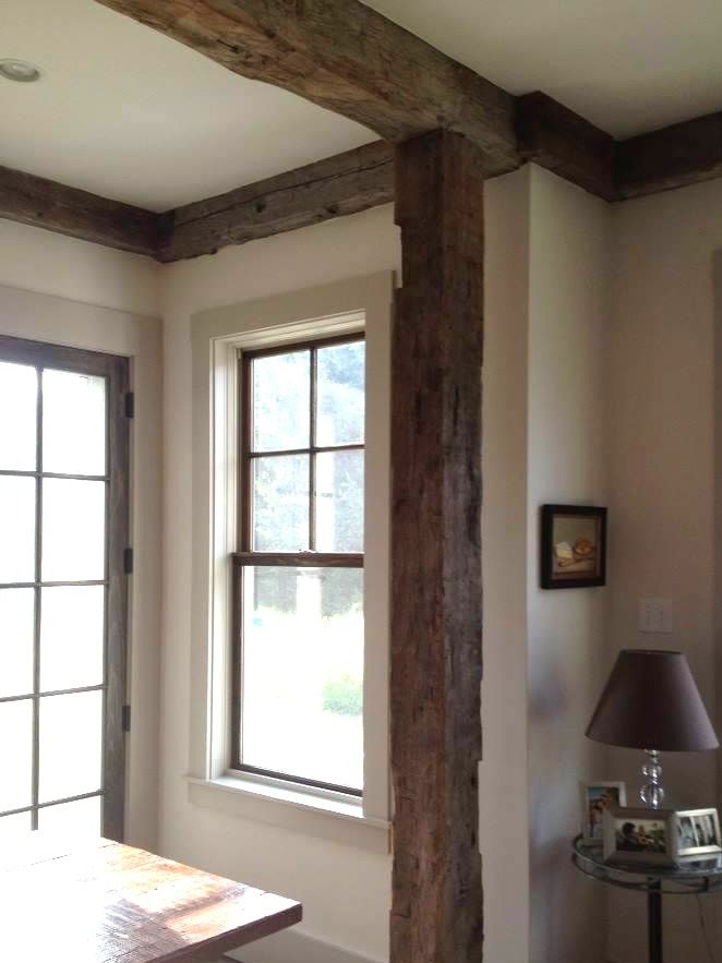 Reclaimed timber beams frame a warm, traditional New England farmhouse interior.
